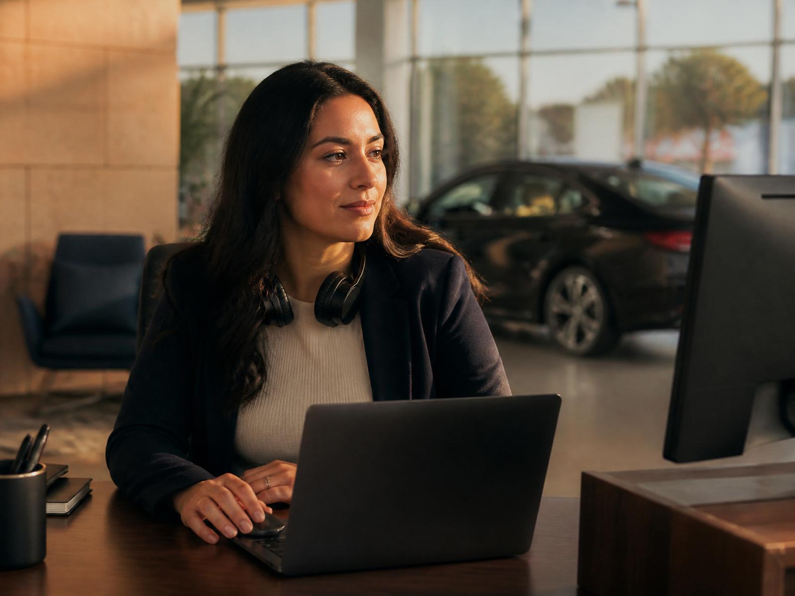 BDC coordinator at a car dealership desk, calmly handling incoming buyer questions